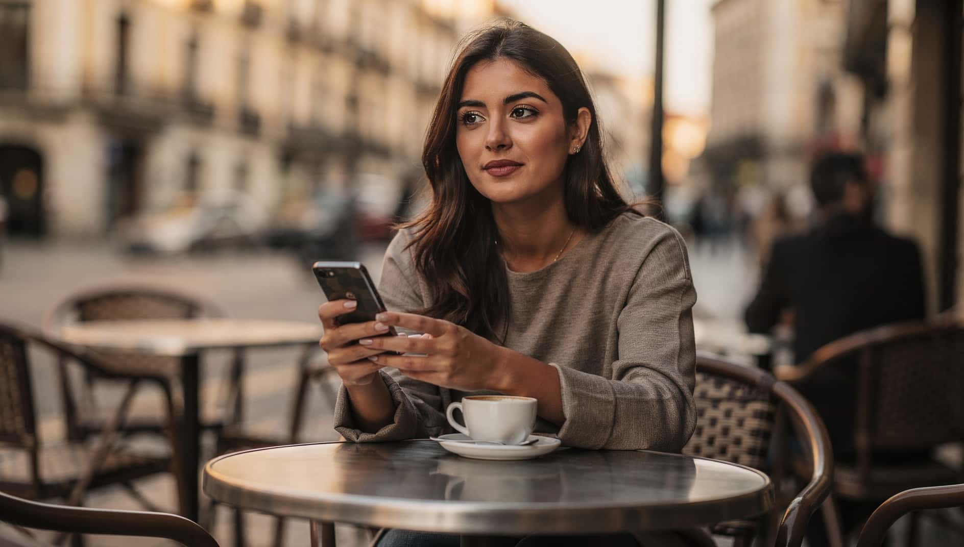 Mujer joven usando un móvil Android en una terraza de Madrid