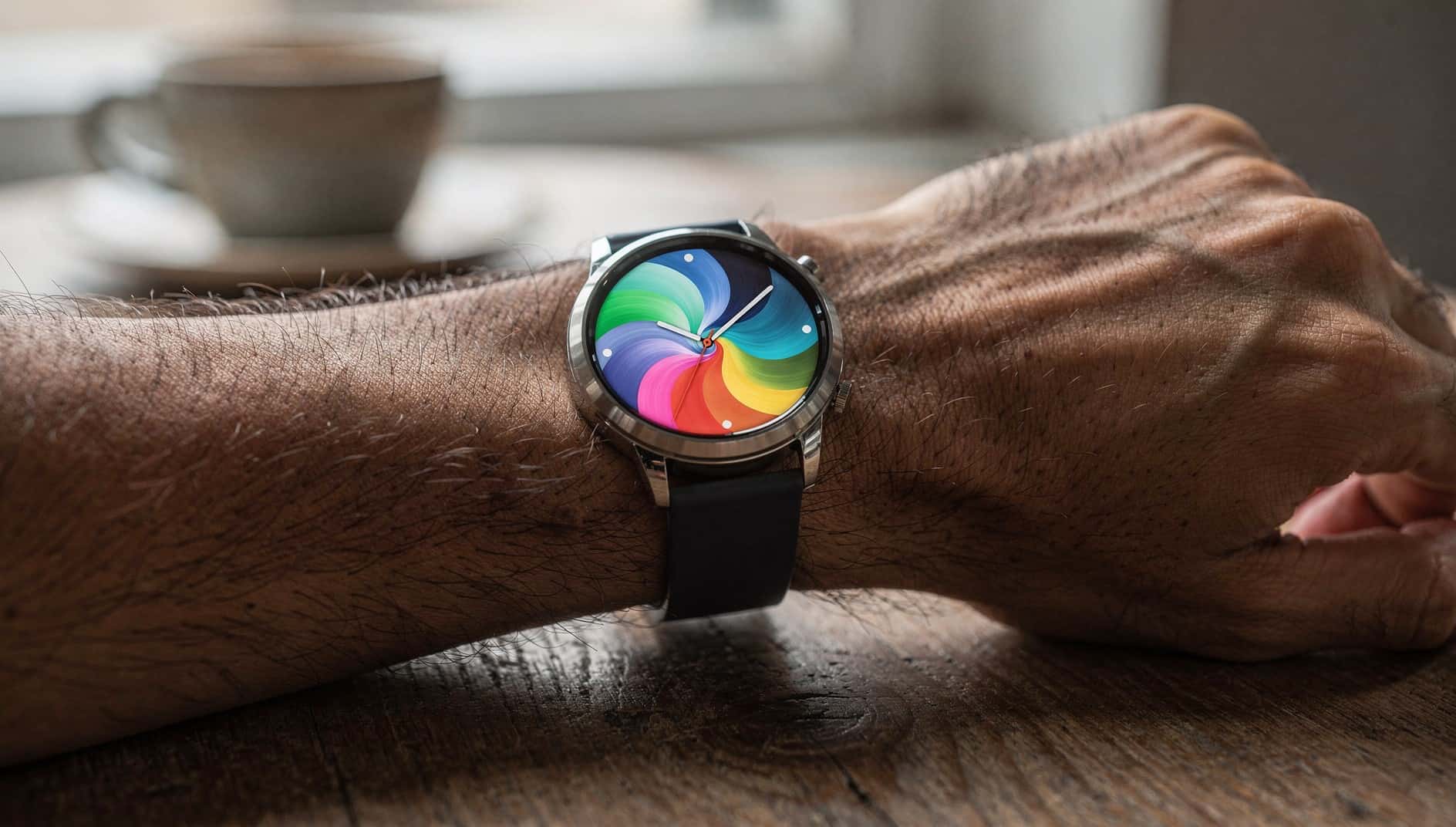 Reloj inteligente redondo en la muñeca con una esfera de colores