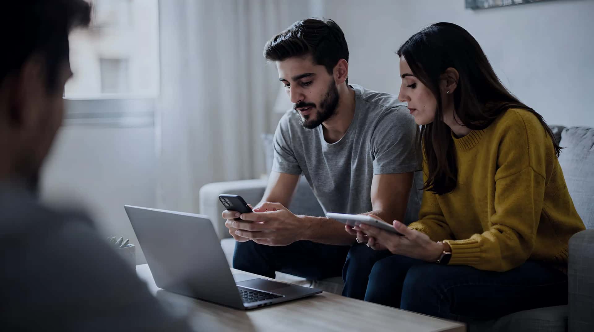 Tres amigos prueban un móvil Android, una tablet y un portátil en un salón