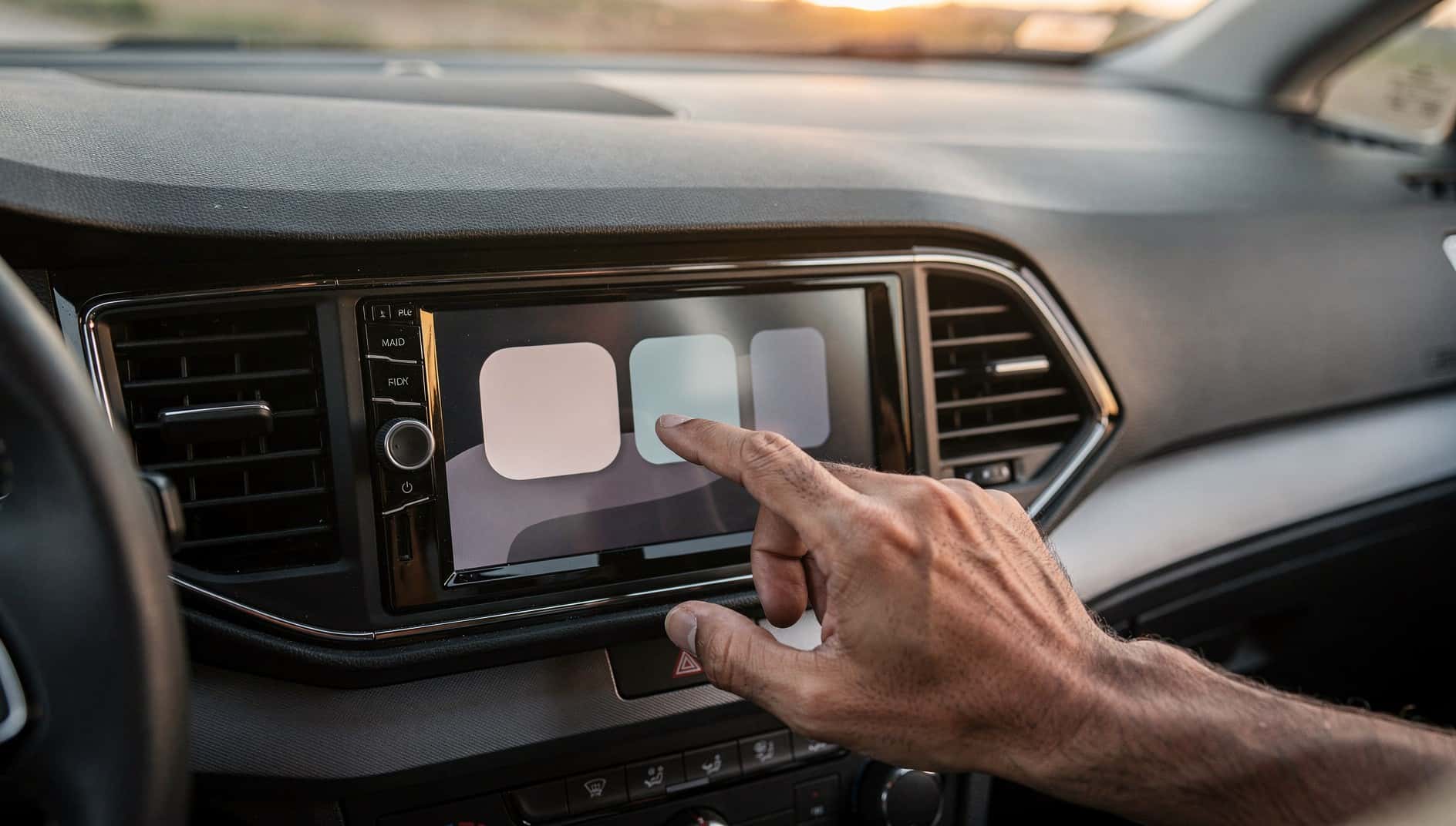 Mano que toca la pantalla táctil de una radio instalada en el salpicadero de un coche