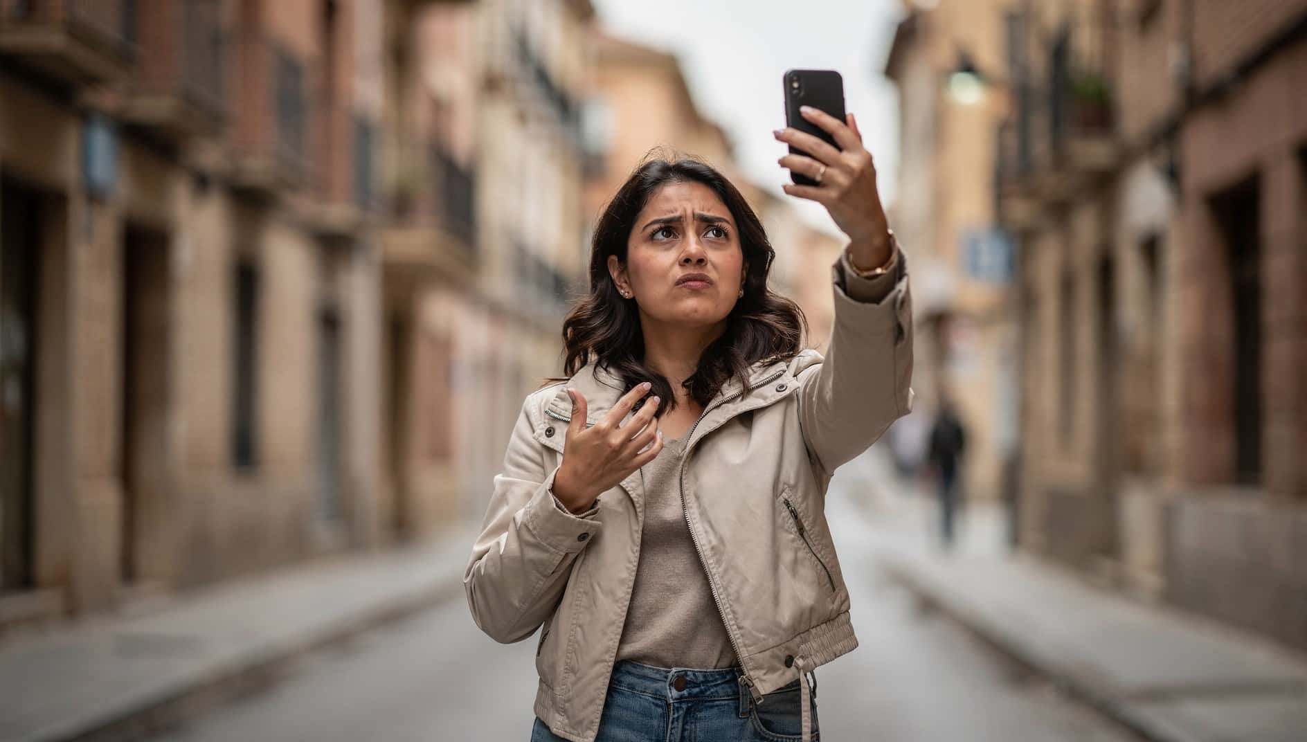 Mujer en la calle levanta el móvil buscando cobertura