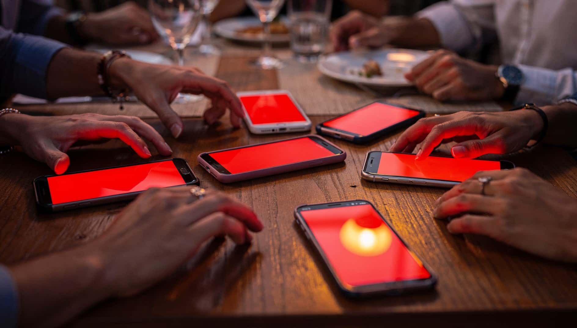 Varios móviles sobre la mesa de un restaurante se encienden a la vez en rojo