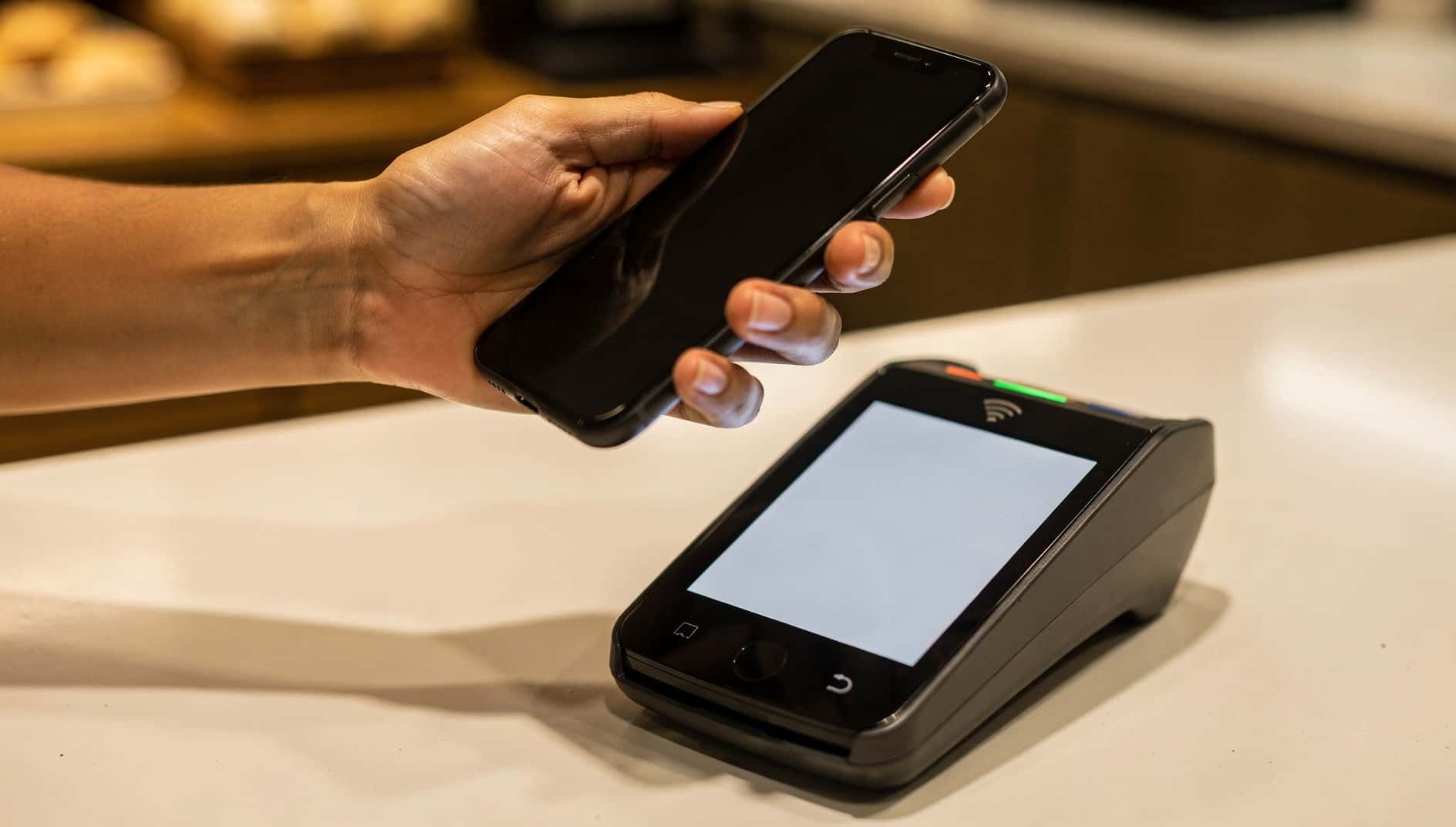 Mano que acerca un móvil a un datáfono para pagar sin contacto