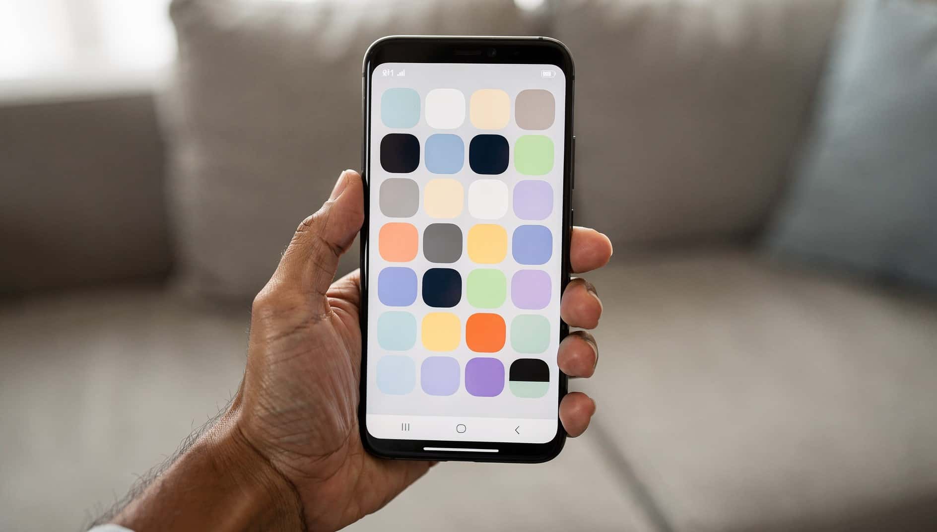 Mano que sostiene un móvil con un icono de aplicación en gris entre los demás