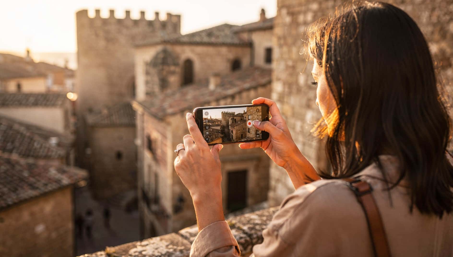 Mujer hace una foto con el móvil a un casco antiguo al atardecer