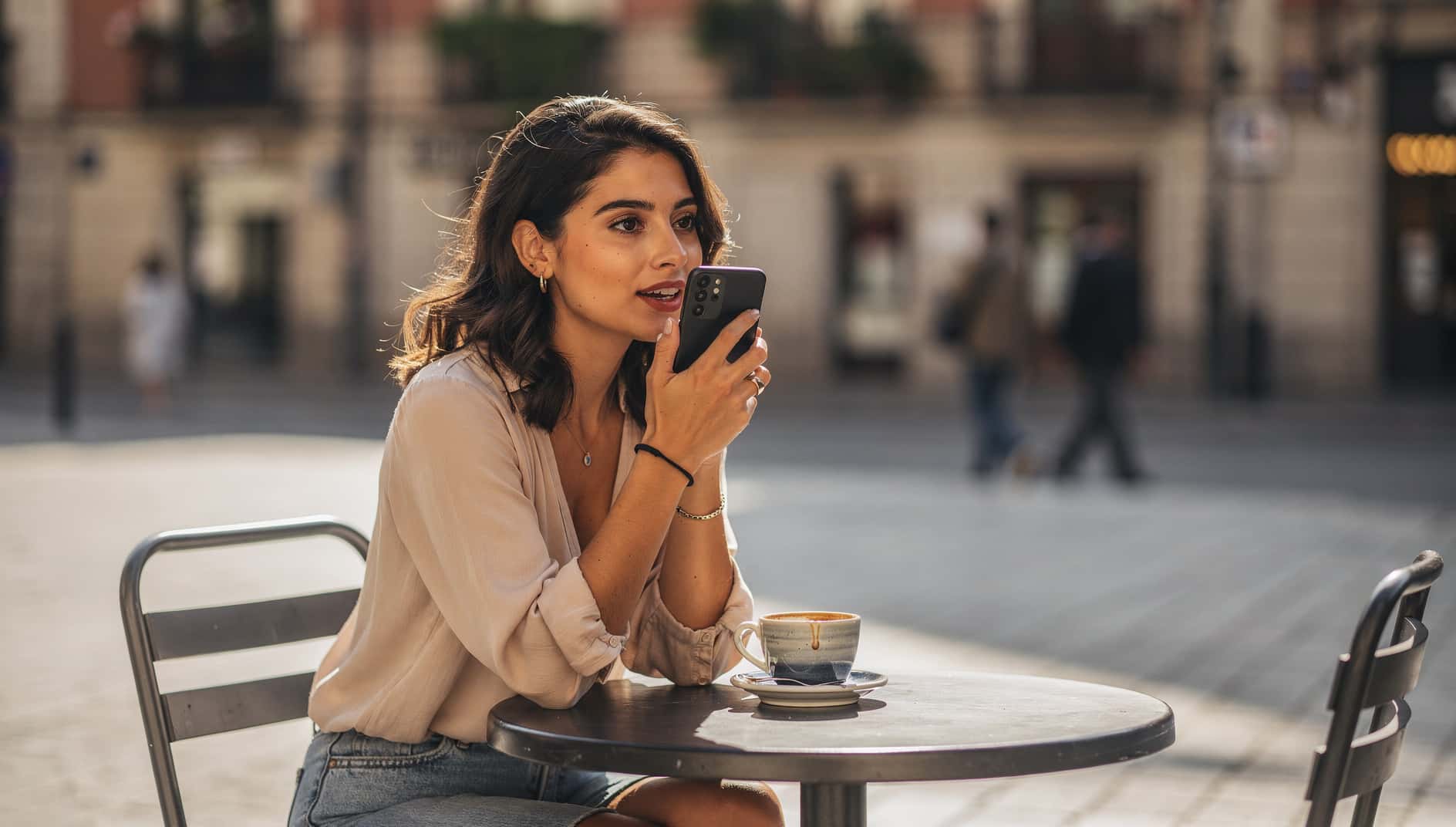Mujer joven en una terraza hablando con un asistente de IA en su móvil Android